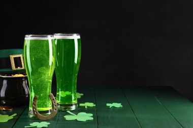 St. Patrick 'in gündüz partisi. Yeşil bira, leprikon şapka, bir küp altın, at nalı ve ahşap masa üzerindeki dekoratif yonca yaprakları. Metin için boşluk