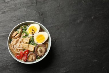 Erişte çorbası. Bir kase lezzetli ramen ve siyah masa, üst manzara. Metin için boşluk