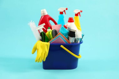 Açık mavi arka planda kovadaki farklı temizlik ürünleri