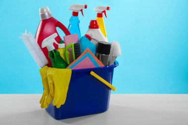 Açık mavi arkaplan ile ahşap masadaki farklı temizlik ürünleri, metin için yer