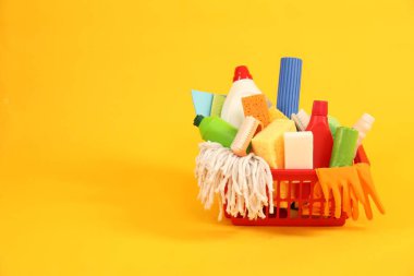 Sarı arkaplanda plastik sepette farklı temizlik ürünleri, metin için yer