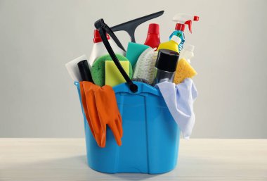 Tahta masadaki kovadaki farklı temizlik ürünleri gri arka planda