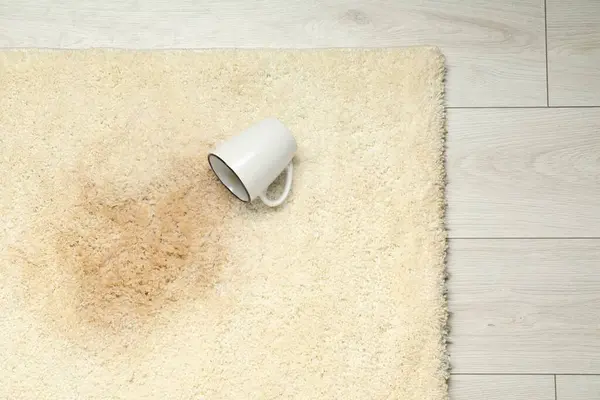 Overturned cup and spilled drink on beige carpet, top view. Space for text
