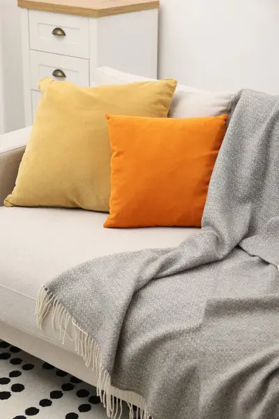 Soft pillows and blanket on sofa indoors