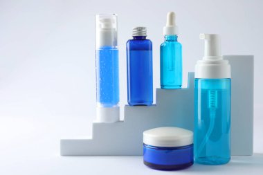 Merdivenlerde beyaz arka planda lüks kozmetik ürünler serisi. Metin için boşluk