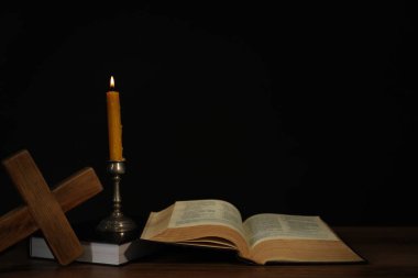 Kilise mumu, İncil ve haç ahşap masa üzerinde siyah arkaplan, metin için boşluk