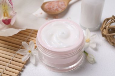 Beyaz masa üzerinde kozmetik ürünleri ve çiçekleri olan güzel bir spa kompozisyonu