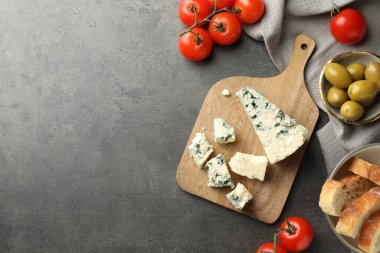 Tahta kesme tahtasıyla düz kompozisyon ve koyu dokulu masa üzerinde ürünler. Metin için boşluk