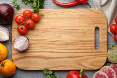 Gri ahşap masa üzerinde kesim tahtası ve ürünlerle düz kompozisyon