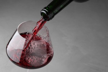 Gri masada cama lezzetli kırmızı şarap dökmek, yakın plan. Metin için boşluk