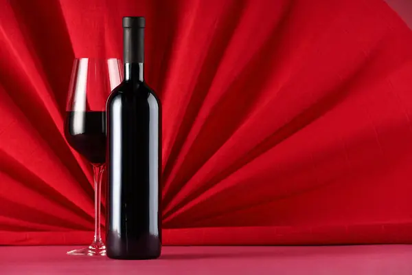 Stylish presentation of delicious red wine in bottle and glass on color background. Space for text