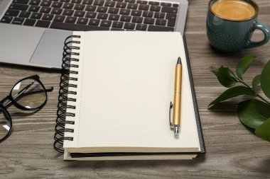 Defter, dizüstü bilgisayar ve kalem ahşap masada.