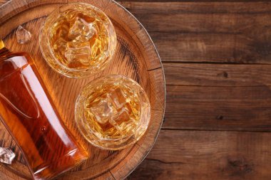 Bardakta buz küplü viski, ahşap masada şişe ve fıçı, üst manzara. Metin için boşluk