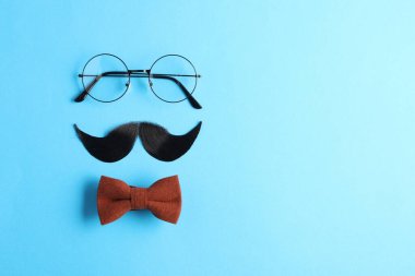 Yapay bıyık, papyon ve açık mavi arka planda gözlük. Metin için boşluk