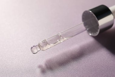 Menekşe arka planında nemlendirici serumu olan boru, yakın plan.