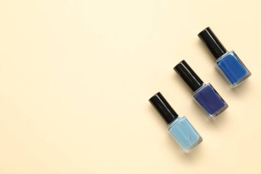 Parlak tırnak cilasını bej arka planda şişelere, düz yere. Metin için boşluk