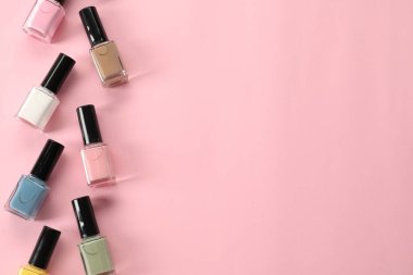 Pastel ojeler pembe arka planda şişelerde, düz yerde. Metin için boşluk