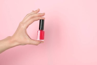 Pembe arka planda tırnak cilası tutan kadın, yakın plan. Metin için boşluk