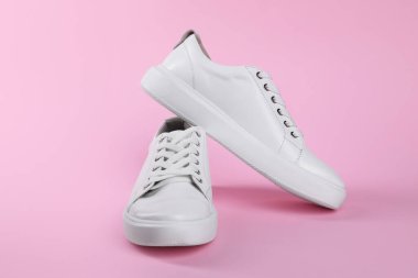 Pembe arka planda bir çift şık beyaz spor ayakkabı