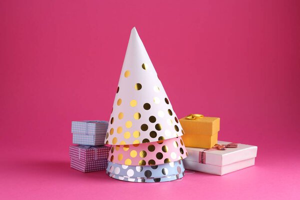 Party hats and gift boxes on pink background