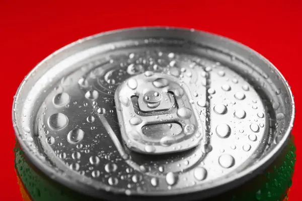 Energy drink in wet can on red background, closeup