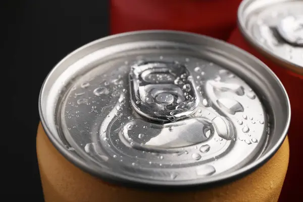 Energy drinks in wet cans on dark background, closeup