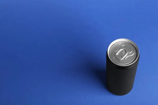 Energy drink in black can on blue background, above view. Space for text