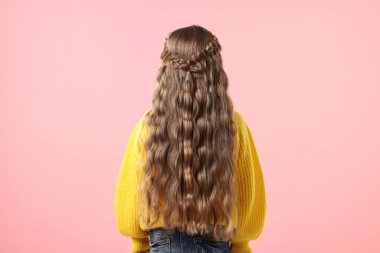 Pembe arka planda örgülü saçları olan küçük bir kız.