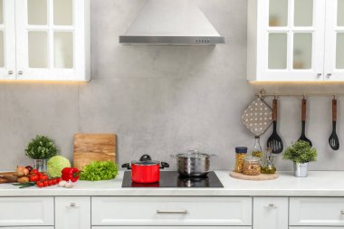 Yemek pişiriyorum. Tencere ve taze sebzeler mutfakta tezgahın üstünde.