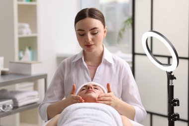 Kozmetik uzmanı klinikteki müşteriye yüz masajı yapıyor.