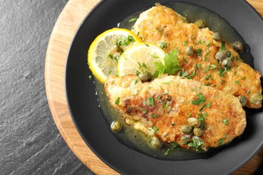 Delicious chicken piccata on black table, top view clipart