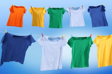 Mavi gökyüzüne karşı çamaşır ipinde kuruyan renkli tişörtler.