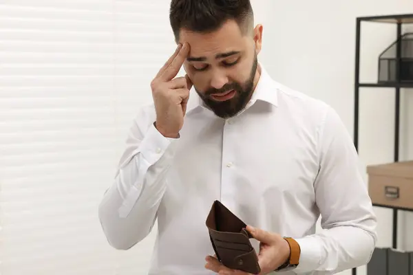 Upset man with empty wallet in office