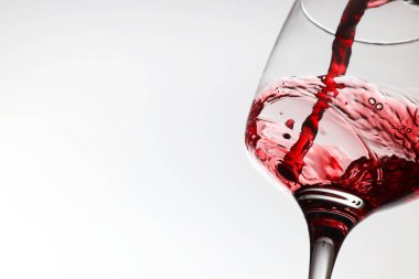 Beyaz arka planda cam bardaklara lezzetli kırmızı şarap dökmek, yakın plan. Metin için boşluk