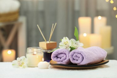 Bulanık arka planda beyaz havluyla farklı spa ürünleri ve çiçeklerle güzel bir kompozisyon