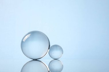 Ayna yüzeyinde şeffaf cam toplar, ışık arka planına karşı. Metin için boşluk