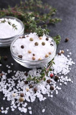 Taze kekikli tuz ve koyu gri desenli masada biber. Yakın plan.