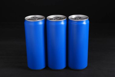 Enerji içecekleri siyah ahşap masada mavi kutularda.