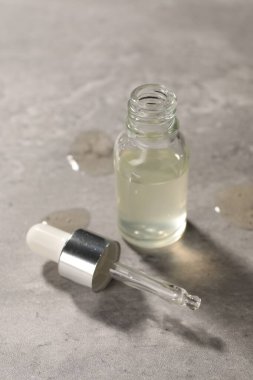 Gri dokulu arka planda boru ve bir şişe nemlendirici serum.