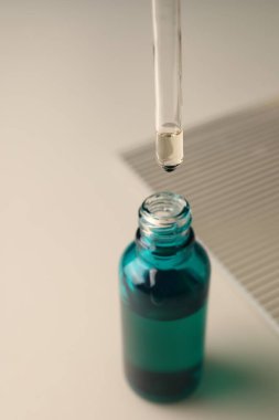 Nemlendirici serumu pipetten hafif arka planda şişeye damlatıyor.