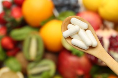 Kaşıkta vitamin hapları, taze meyveler, üst manzara. Metin için boşluk