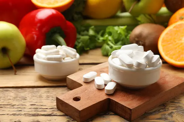 Dietary supplements. Pills in bowls and food products on wooden table