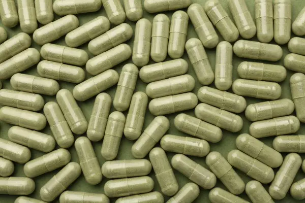 Vitamin capsules on olive background, flat lay