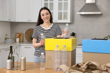 Mutfaktaki çöpleri ayıran gülümseyen kadın.