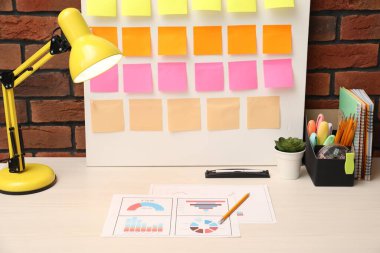 İş süreci planlaması ve optimizasyonu. Masada renkli kağıt notlar ve diğer kırtasiye malzemesi olan işyeri