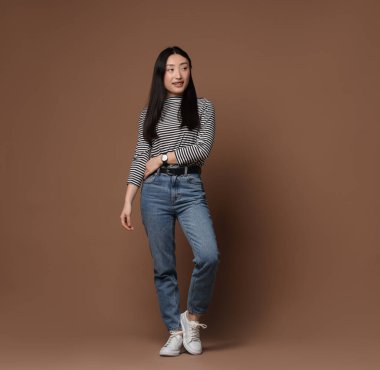 Kahverengi arka planda gülümseyen kadının tam boy portresi. Metin için boşluk