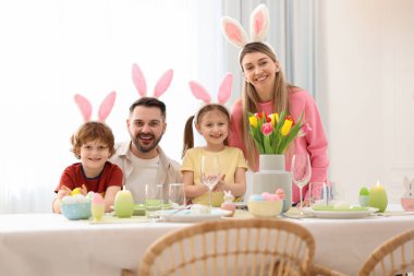 Paskalya kutlaması. Odada servis masasında tavşan kulaklı mutlu bir ailenin portresi.