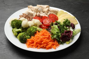 Dengeli beslenme ve sağlıklı yiyecekler. Siyah masadaki farklı lezzetli ürünlerin olduğu tabaklar, yakın plan.