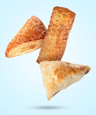 Açık mavi arkaplana düşen farklı lezzetli puf börekleri