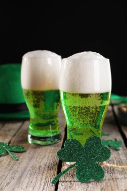 St. Patrick 'in gündüz partisi. Yeşil bira ve ahşap masa üzerindeki dekoratif yoncalar.